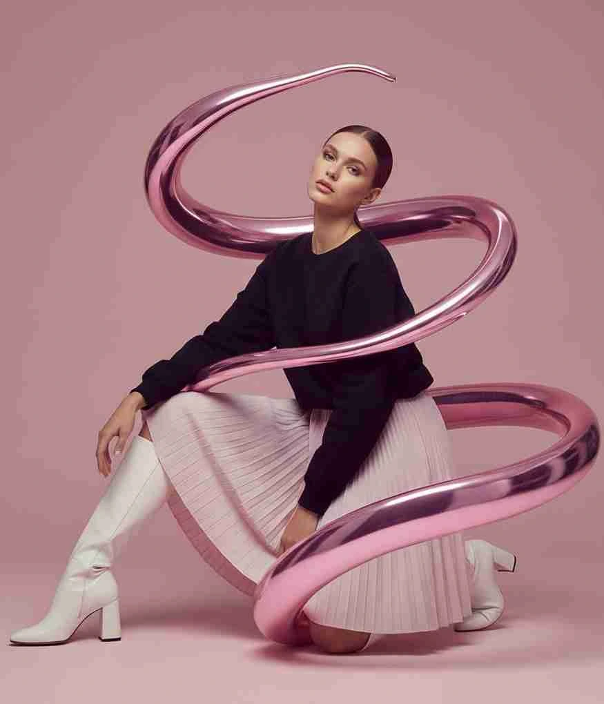 Woman in a minimalist fashion photo shoot with a metallic pink spiral sculpture